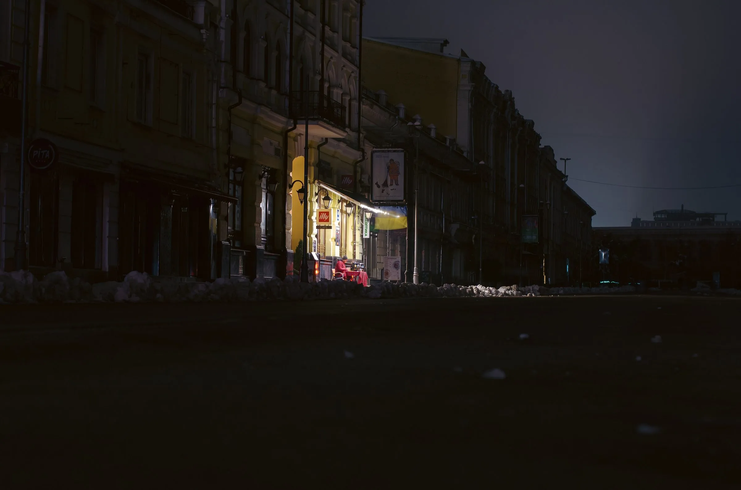Темна вулиця в центрі Києва під час блекауту, світиться лише одна кав'ярня
